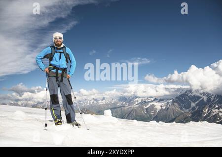 Porträt eines bärtigen Reiseleiters mit Hut und Sonnenbrille vor dem Hintergrund schneebedeckter Berge Stockfoto