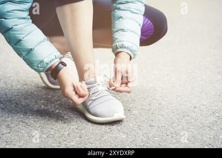 Läuferin, die Schnürsenkel bindet, um ihre Schuhe auf der Straße im Park zu joggen. Laufschuhe, Schnürsenkel. Übungskonzept. Sportlicher Lifestyle. Vintage-Style Stockfoto