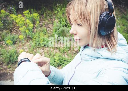 Porträt Junge Fitness-Frau, die ihre Smartwatch ansieht, während sie eine Pause vom Sporttraining macht. Sportsfrau überprüft Puls auf Fitness-Smartwatch d Stockfoto