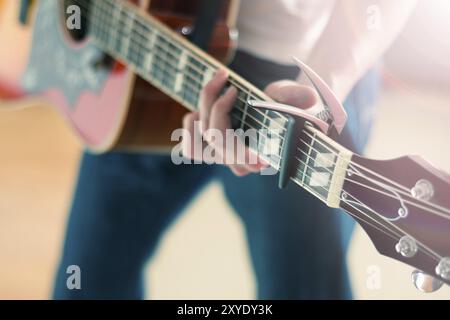 Junge Menschen spielen eine Sunburst Westerngitarre: Ausschneiden, verschwommen Stockfoto