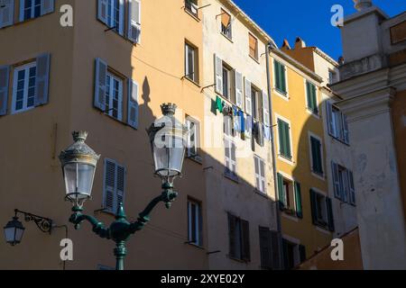 Ajaccio, Korsika - 11. Oktober 2019: Sonnendurchflutete Fassade mit hängender Wäscherei und Straßenlampe. Stockfoto