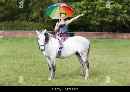 Pippi Langstrumpf sitzt seitlich mit farbenfrohem Regenschirm auf dem kleinen Onkel Stockfoto