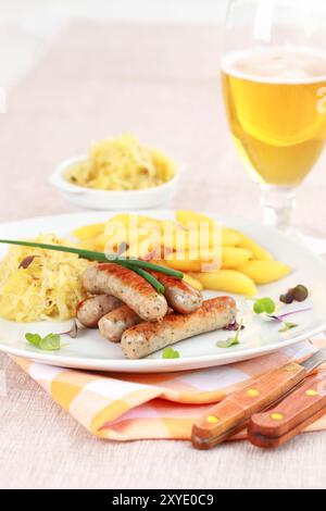 Traditionelles deutsches Gericht mit Kalbswurst mit Sauerkraut und Nudelbrötchen mit Bier Stockfoto