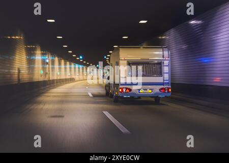 Auto mit Wohnwagen fährt durch einen Autobahntunnel Stockfoto