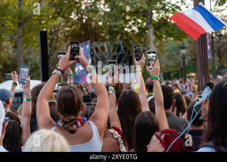 Paris, Frankreich. August 2024. Zuschauer bei der Eröffnungszeremonie der Paralympischen Spiele 2024 in Paris auf der Avenue des Champs-Elysées fangen die vorbeifahrenden Athleten mit ihren Smartphones ein. Quelle: Fabienne Koch/Alamy Live News Stockfoto