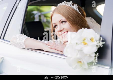 Nahaufnahme Porträt einer wunderschönen Braut mit einem Hochzeitsstrauß im Fenster eines Hochzeitsautos. Das Konzept des Hochzeitsglücks Stockfoto