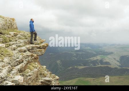 Bärtiger Hipster-Tourist, der am Felsenrand steht und auf einem epischen Plateau in die Ferne blickt. Das Konzept des Tourismus Stockfoto