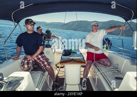 3 Männer einer Segelcrew am Heck ihrer Yacht an der kroatischen Küste Stockfoto