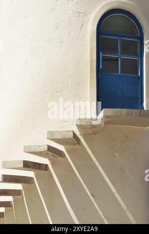 Eine Treppe führt zu einer Tür in Zementwand mit Licht und Schatten Stockfoto
