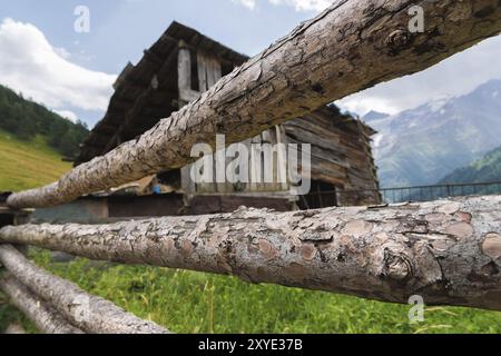 Nahaufnahme eines alten hölzernen Zauns auf dem Hintergrund einer alten hölzernen Scheune in einem kaukasischen Bergdorf Stockfoto