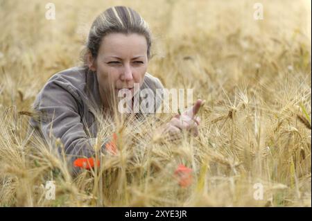 Eine junge Frau, die auf einem Getreidefeld sitzt Stockfoto