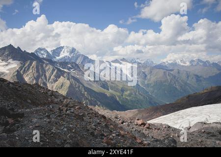 Berglandschaft staubiger, schmutziger vulkanischer Hang mit einem rissigen, schmelzenden Gletscher vor dem Hintergrund der Kaukasusberge. Globale Erwärmung. Gletscher Stockfoto