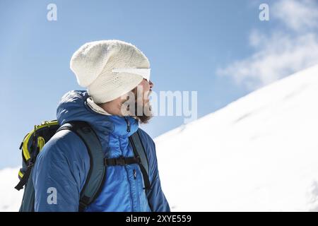 Porträt eines bärtigen Reiseleiters mit Hut und Sonnenbrille vor dem Hintergrund schneebedeckter Berge Stockfoto