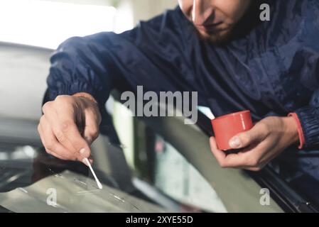 Nahaufnahme Auto Glasierer Arbeiter Befestigung und Reparatur Windschutzscheibe oder Windschutzscheibe eines Autos in Auto-Service-Station Garage Stockfoto