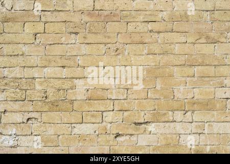 Strukturierter Hintergrund eines Steinsteins aus gelbem antediluvischem Mauerwerk. Teilweise zerstörte Wand. Backsteingrunge-Hintergrund im Vintage-Stil Stockfoto