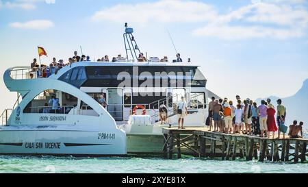 Alcudia, Spanien 14.09.2011, Leute auf hölzernem Pier warten auf Boot. Das Boot legt am Pier auf den Balearen in Playa de Muro an. Touristenziel Stockfoto