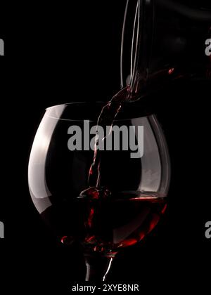 Glas Rotwein mit einem alten rustikalen Dekanter auf dunklem Hintergrund Stockfoto