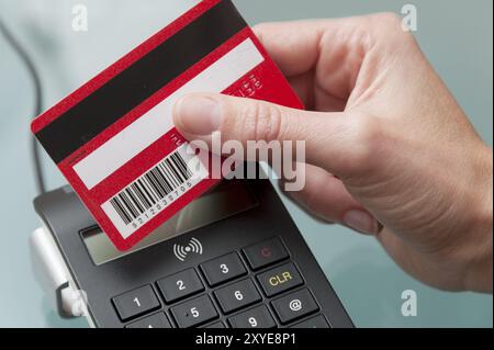 Eine Hand hält eine elektronische Karte an einem Lesegerät Stockfoto