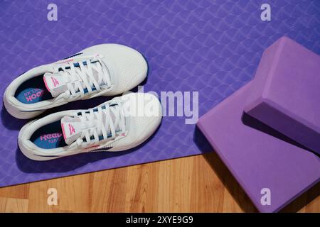 Straßburg, Frankreich - August 2024: Neue Trainingsschuhe Reebok Nano X4. Neue weibliche Trainingsschuhe auf Yogamatte und Holzboden. Stylische farbenfrohe Schuhe f Stockfoto