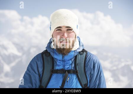 Porträt eines bärtigen Reiseleiters mit Hut vor dem Hintergrund schneebedeckter Berge Stockfoto