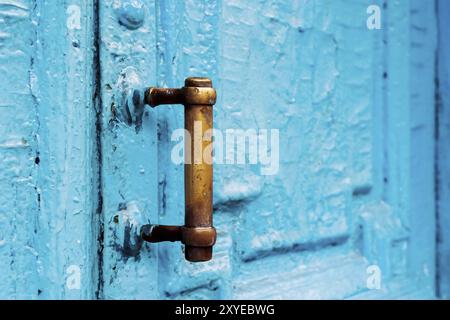 Nahaufnahme von Schlüssellöchern mit Vorhängen und einem Griff auf der blauen, oft gemalten, gerissenen Holztür mit doppeltem Zylinder des letzten Jahrhunderts mit einer Pos. Stockfoto