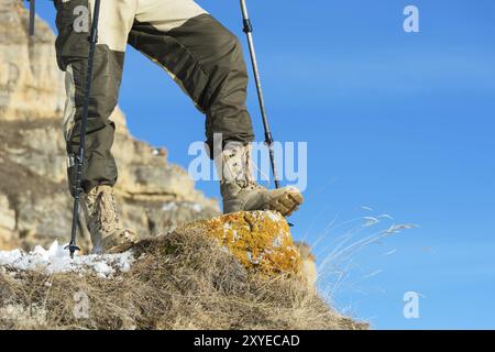 Nahaufnahme des Fußes eines Touristen in Trekkingschuhen mit Stöcken für Nordic Walking auf einem Felsstein in den kaukasischen Bergen Stockfoto