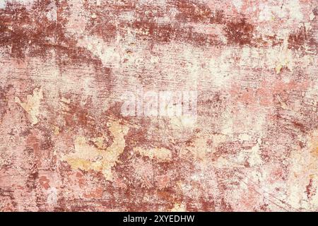 Rosa-rot strukturierter Hintergrund aus mehrschichtiger abblätternder Farbe an der Wand. Mischen verschiedener Farben von Farben in den aufgespaltenen Schichten auf der Oberfläche. Grunge Stockfoto