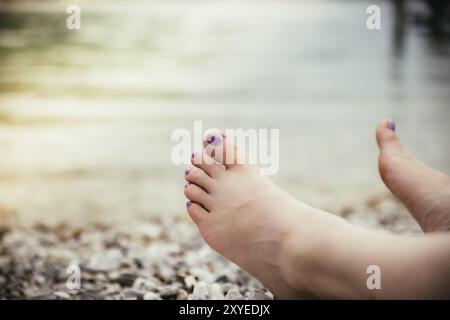 Füße einer Frau mit violettem Nagellack am Strand Stockfoto