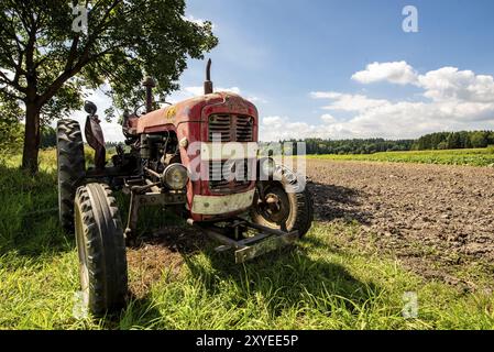 Ein alter roter, rostiger Traktor auf dem Feld. Sonniger Sommertag. Kopierbereich Stockfoto