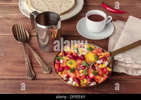 Mexikanisches Frühstück. Huevos Rancheros, das gebratene Eier, mit dem Pico de gallo Salat, heiße Schokolade und Tortillas auf einem dunklen Holzmöbeln im Landhausstil Hintergrund Stockfoto