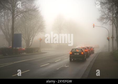 Das Auto hält im Nebel vor einer roten Ampel an einer Kreuzung Stockfoto