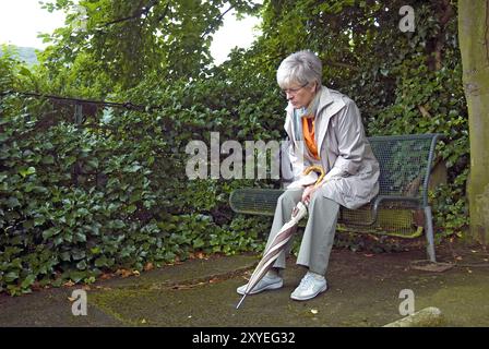 Einsame Frau, die auf einer Parkbank sitzt Stockfoto