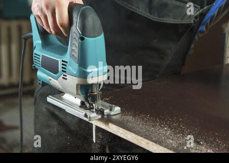 Nahaufnahme ein Zimmermann sägt ein elektrisches Stichsäge Holz Stockfoto