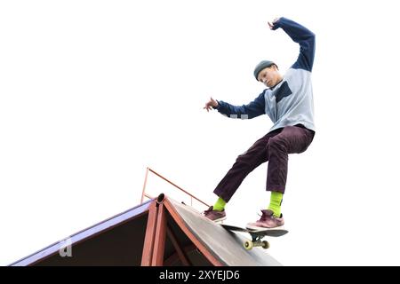 Teenager Skater in Hoodie Sweatshirt und Jeans gleiten über eine Rampe auf einem Skateboard isoliert auf weiß Stockfoto