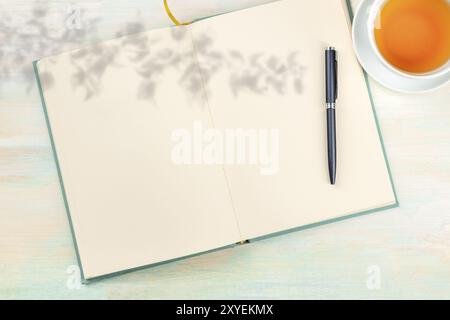 Eine offene Journal mit einem organischen Schatten, einen Stift und eine Tasse Tee, Schuß von der Oberseite, auf hellem Hintergrund mit Kopie Raum Stockfoto