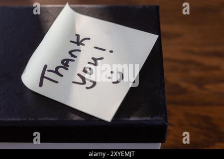 Eine Box mit einer Notiz mit der Aufschrift „Danke“, auf der ein Lichtstrahl auf der Notiz leuchtet. Stockfoto