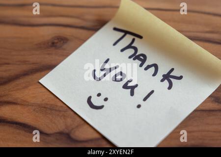 Ein Dankeschön steht auf einem Blatt Papier. Die Nachricht lächelt und sagt: „Danke!“ Darauf Stockfoto