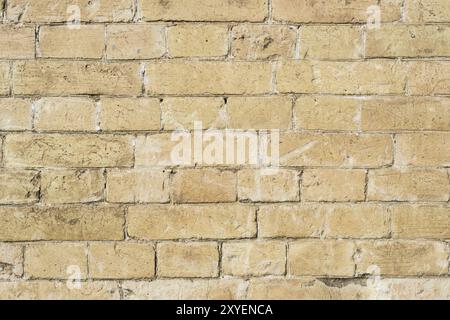 Strukturierter Hintergrund eines Steinsteins aus gelbem antediluvischem Mauerwerk. Teilweise zerstörte Wand. Backsteingrunge-Hintergrund im Vintage-Stil Stockfoto