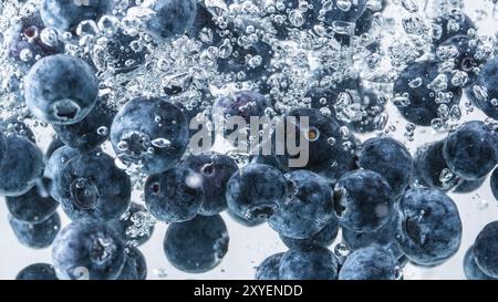 Heidelbeeren in das Wasser sinken mit Luftblasen weißer Hintergrund Stockfoto