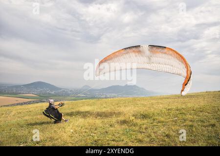 Der Gleitschirmflieger öffnet seinen Fallschirm, bevor er vom Berg im Nordkaukasus abhebt. Füllen Sie den Fallschirmflügel vor dem Start mit Luft Stockfoto