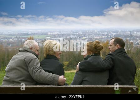 Junge und alte Paare sitzen auf einer Bank Stockfoto