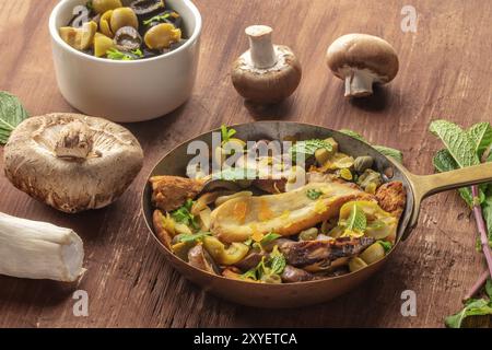 Ein rustikales Pilze und Oliven saute mit Minze und Steinpilzen auf einem dunklen Hintergrund Stockfoto