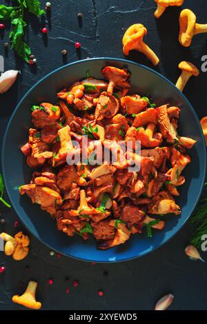 Gericht mit frittierten Pfifferlingen, Kräutern und Gewürzen auf schwarzem Schieferbrett. Draufsicht. Hintergrund zu Lebensmitteln. Stockfoto