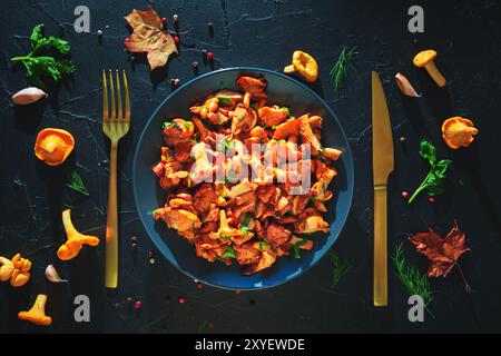 Gericht mit frittierten Pfifferlingen, Kräutern und Gewürzen auf schwarzem Schieferbrett. Draufsicht. Hintergrund zu Lebensmitteln. Stockfoto