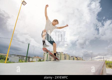 Junge Skateboarder in einem Skatepark, der einen manuellen Trick auf einem Skateboard gegen einen Himmel und Gewitterwolken macht Stockfoto