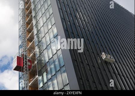 Materialzug und Arbeitsplattform an der Fassade eines Hochhauses Stockfoto