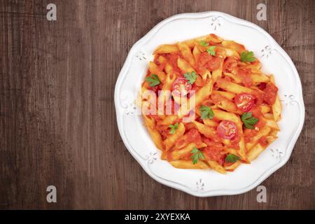 Penne Pasta mit Tomatensauce und Petersilie, Top Shot auf einem dunklen Holzmöbeln im Landhausstil Hintergrund mit Kopie Raum Stockfoto