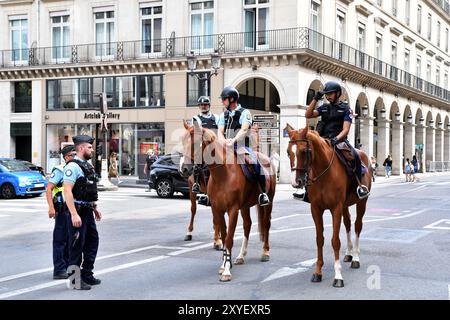 Während der Olympischen Spiele 2024 patrouilliert die berittene Polizei in der Rue de Rivoli in Paris, um Sicherheit und Sicherheit inmitten der hektischen Menschenmassen zu gewährleisten - Paris, Frankreich Stockfoto