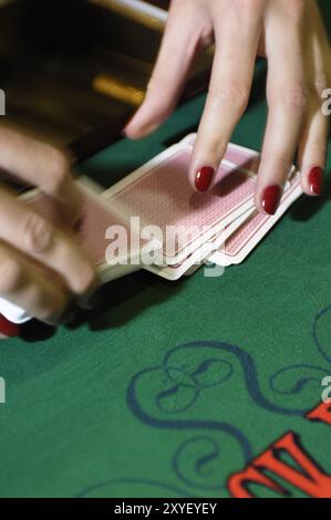 Hände eines Croupier-Händlers an einem Blackjack-Kartentisch, der die Karten in einem Casino mischt Stockfoto