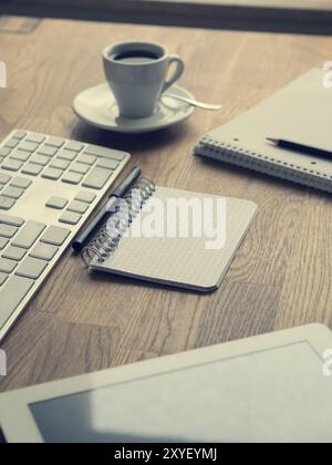 Espresso mit Notebooks und Tastatur auf hölzernen Bürotisch, Hipster Style Hintergrund Stockfoto